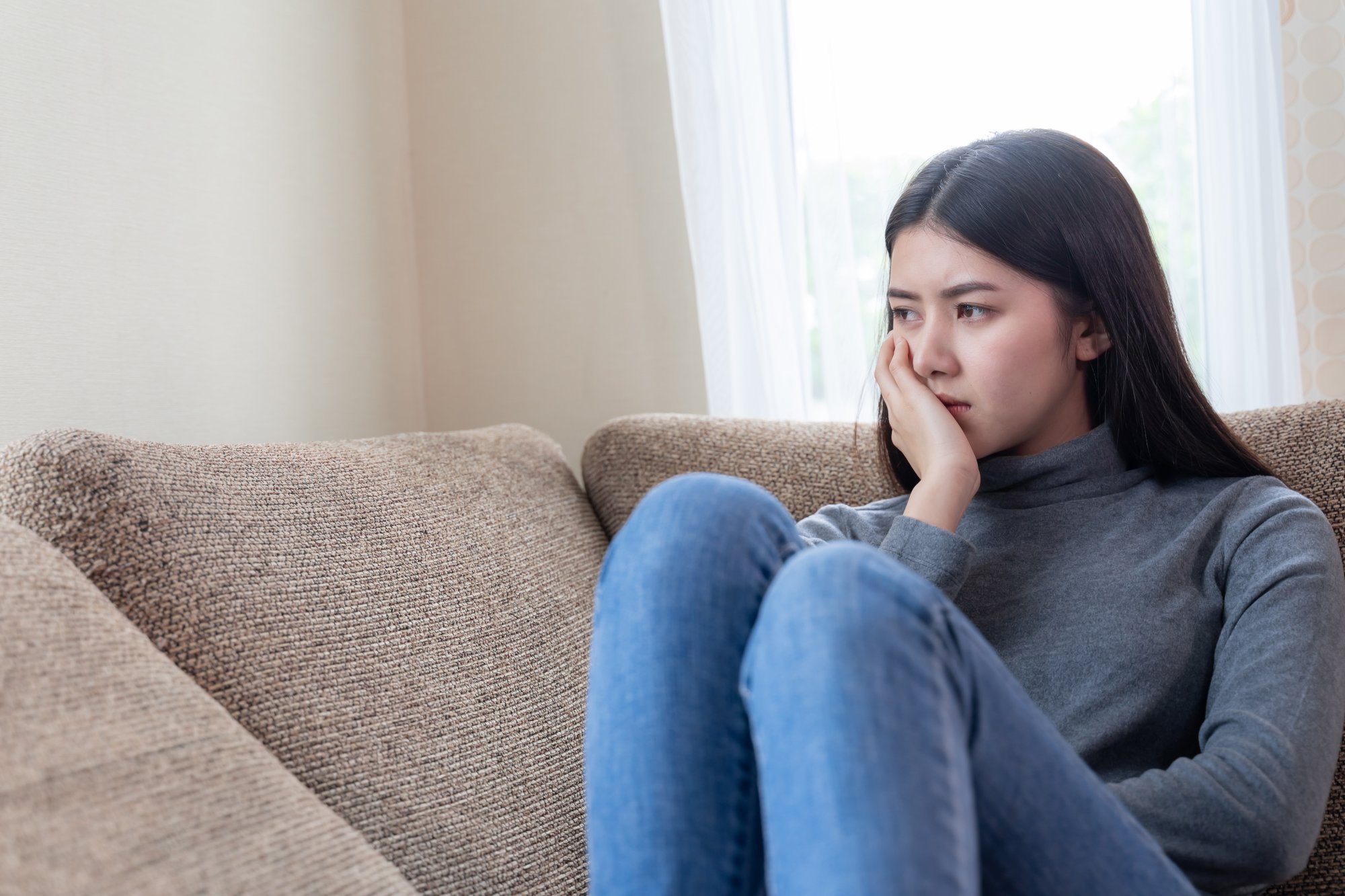 close-up-face-unhappy-asian-pretty-young-woman-sitting-alone-couch
